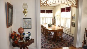 A dining area with a wooden table and chairs, a floral centerpiece, and a patterned rug.