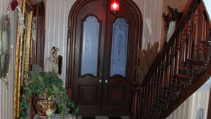 A checkered floor, a wooden staircase, and a door with a red light above it.