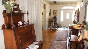 A traditional interior with a wooden cabinet, a table with a lamp, and a chair.