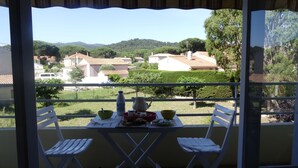 A balcony with a table set for two, overlooking a residential area with houses and greenery.