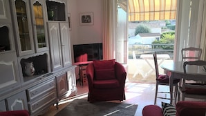 A living room with a red sofa, a TV, and a dining area with a table and chairs.