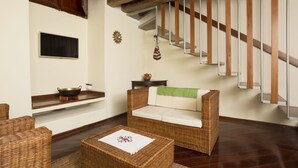 A living room with a wicker sofa, a small table with a placemat, a wooden staircase, and a wall-mounted television. - UNIQUE & STYLISH Boutique-Colonial Loft @ Quito Centro Historic (Quito)
