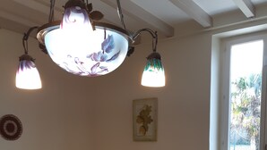 Une pièce confortable avec un lit, une table à manger, des chaises, une lampe et une fenêtre donnant sur un paysage verdoyant.