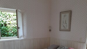 Une chambre à coucher avec un lit, une fenêtre, un radiateur, une horloge murale et un tableau encadré.