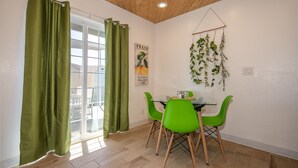 Un espace repas avec une table en verre, des chaises vertes et un plafond en bois.