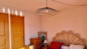 Un dormitorio con cama, armario de madera, cesta de mimbre y una lámpara de pared.
