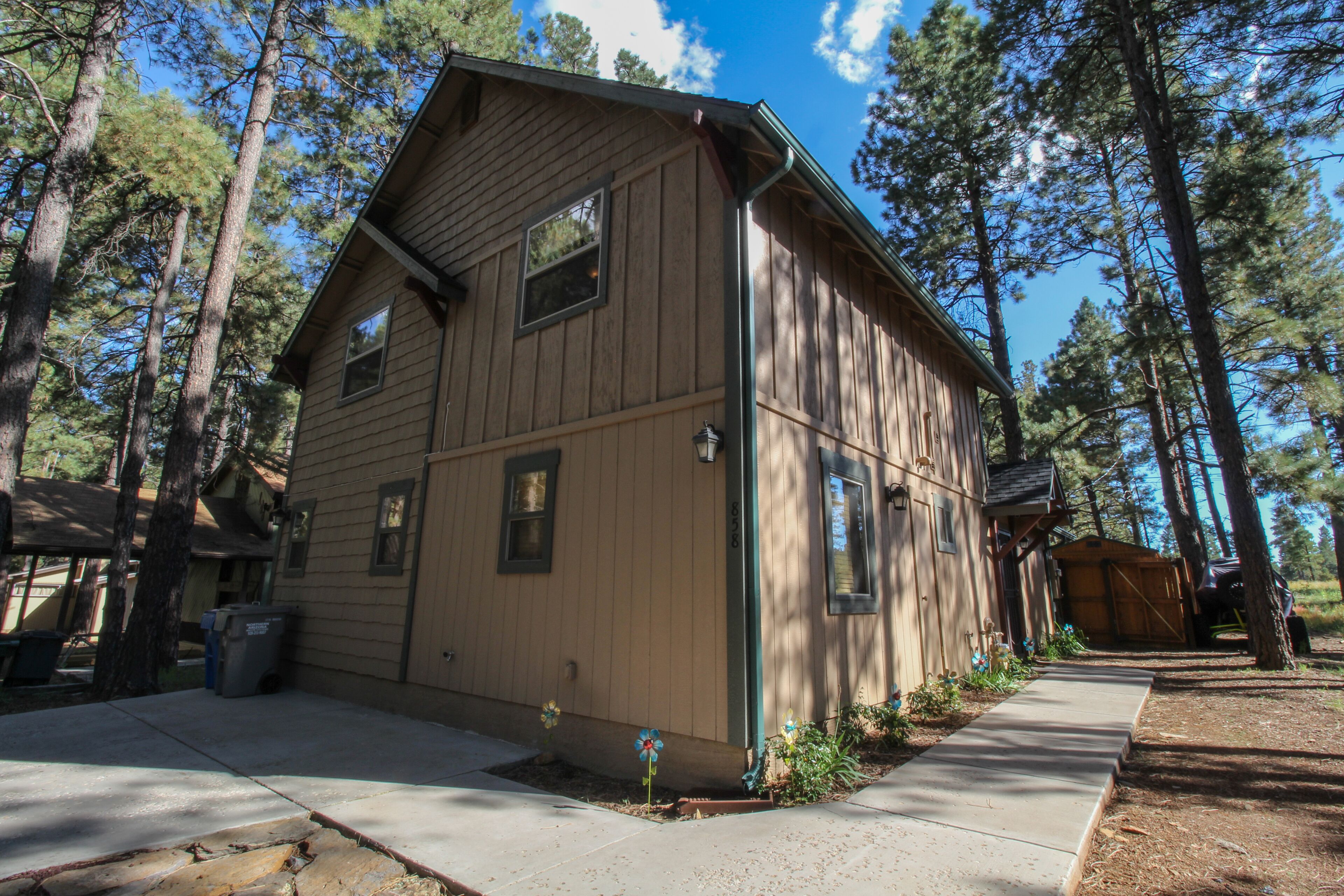 A two-story wooden house with a sloped roof, a front porch, and a visible garage door.