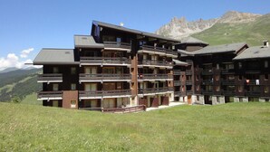 Ein mehrstöckiges Hotel mit Balkonen vor einer Bergkulisse.