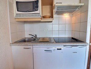A compact kitchen with a microwave, toaster, sink, and dishwasher.