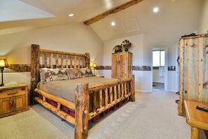 A rustic bedroom with a wooden bed, a wooden wardrobe, and a small table.