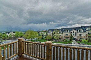 A residential area with a wooden deck railing, houses with multiple stories, and a cloudy sky.