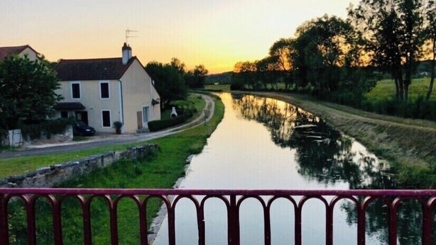 Ein Kanal mit einem Haus links und Bäumen rechts.