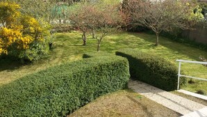 A well-maintained garden with neatly trimmed hedges, a variety of trees, and a stone pathway leading to a white railing. - House 800m from the beaches of Beg Leguer, with enclosed garden with trees (Lannion)