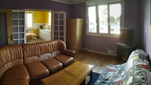 A living room with a brown leather sofa, a wooden coffee table, a television, and a window with a view of the outside. - House 800m from the beaches of Beg Leguer, with enclosed garden with trees (Lannion)
