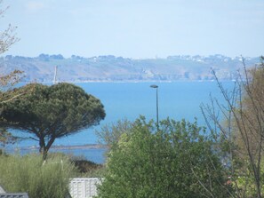 A coastal landscape with a tree, a street lamp, and a view of the sea and distant hills. - House 800m from the beaches of Beg Leguer, with enclosed garden with trees (Lannion)