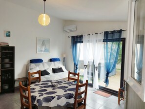 Ein Schlafzimmer mit Bett, Schreibtisch, Stuhl, Bücherregal und Blick ins Freie.