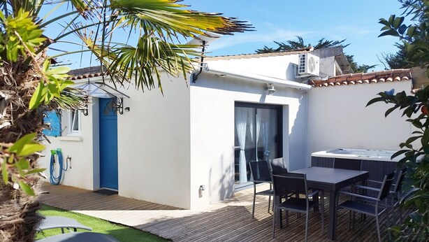 A patio area with a table and chairs, a hot tub, and a small garden with a palm tree. - Charming house Spa Terrace Garden (Angoulins)