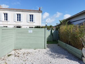 A gated property with a gravel driveway and a building with white walls and shutters.