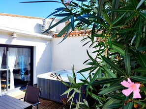 Eine Dachterrasse mit Whirlpool, Holzterrasse und Topfpflanzen.