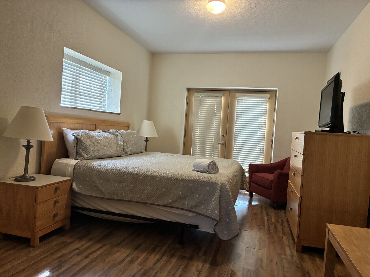 A bedroom with a bed, two bedside tables, a dresser, and a television.