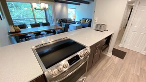 A modern kitchen with a built-in stove, a dining area with a table and chairs, and a view of the outdoors.