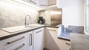 A modern kitchen with white cabinets, stainless steel appliances, and a black coffee maker. - ⭐️⭐️⭐️Cathédrale, bright space in the heart of town (Reims)