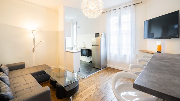A modern living room with a sectional sofa, a glass coffee table, a dining table, and a kitchen area with a refrigerator and microwave. - ⭐️⭐️⭐️Cathédrale, bright space in the heart of town (Reims)
