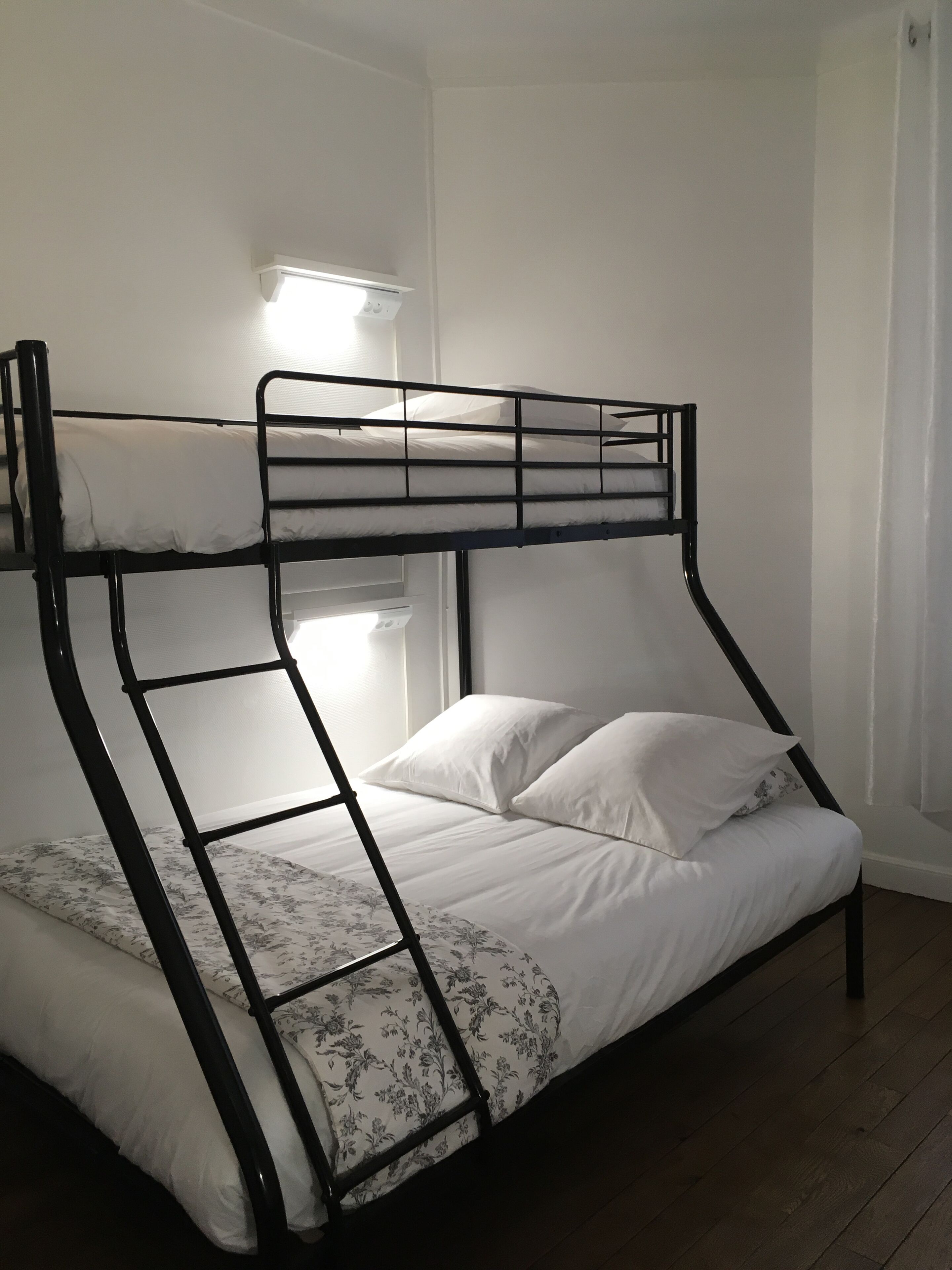 A bunk bed with a ladder, white bedding, and a floral-patterned pillow.