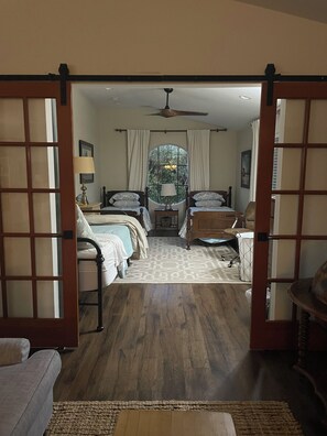 A hotel room with a large bed, two bedside tables, a window with a view, and a ceiling fan.