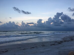 A beach with waves and a cloudy sky.