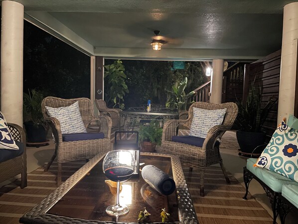An outdoor seating area with wicker furniture, a glass table, and a wine glass.