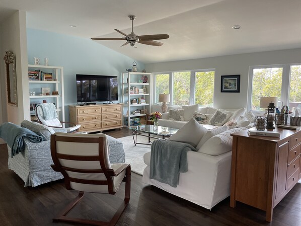 A spacious living room with a large TV, a wooden cabinet, and a white sofa.