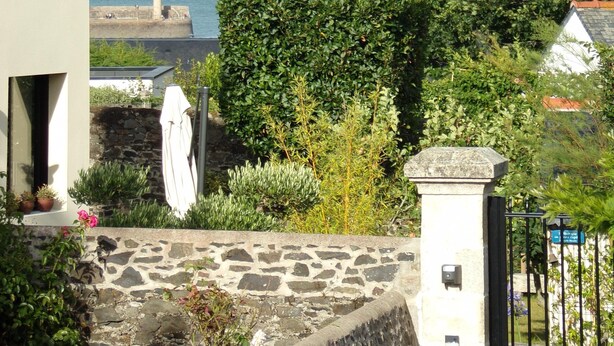 A coastal view with a stone wall, a white umbrella, and a stone pillar. - Quiet studio near the sea (Binic)