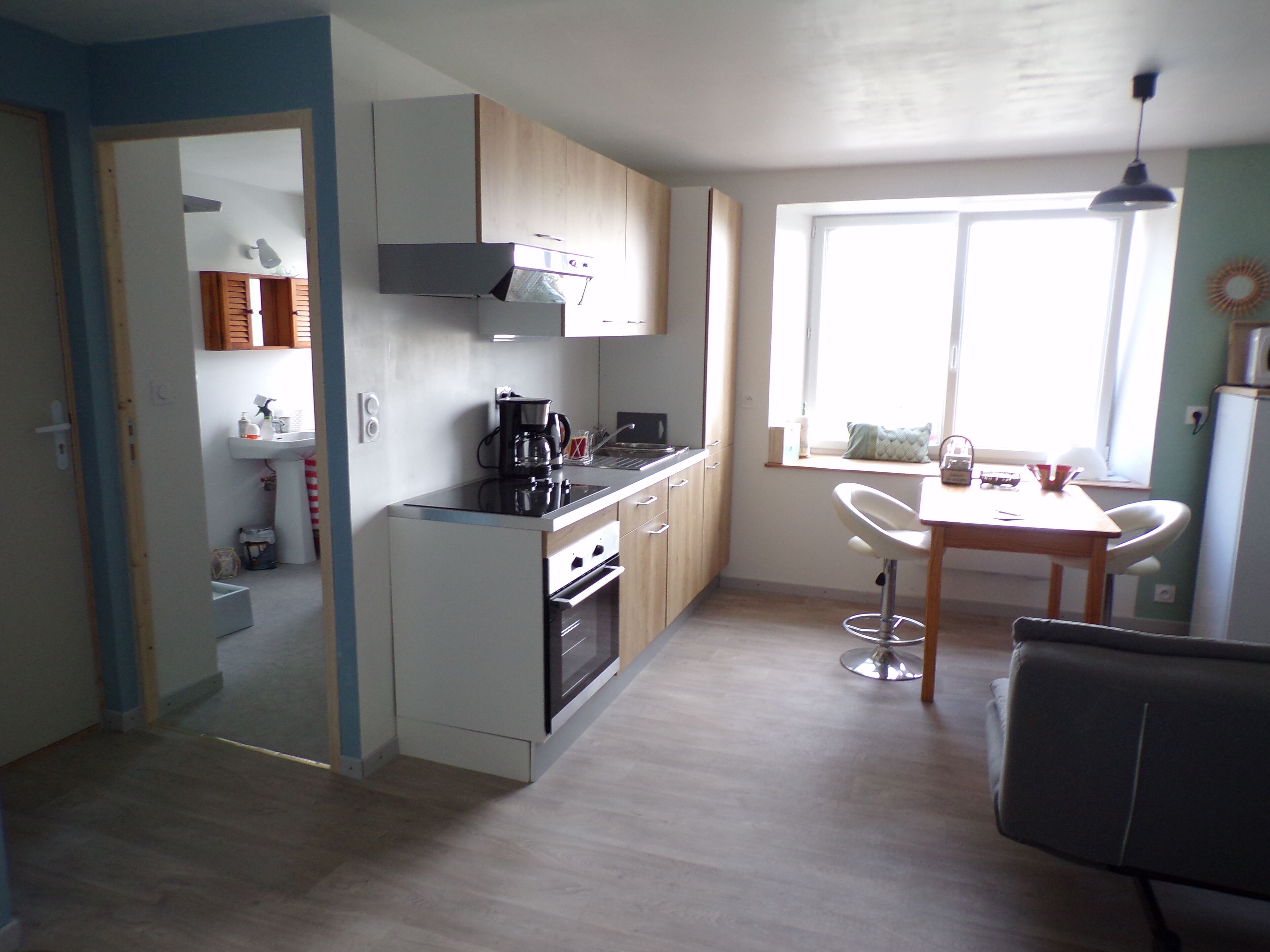 A compact kitchen with a stove, sink, and a dining area with a table and chairs.