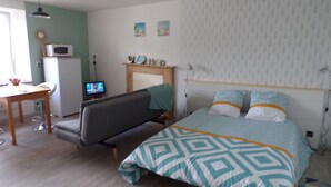 A bedroom with a bed, a desk, a chair, a television, and a microwave. - Quiet studio near the sea (Binic)