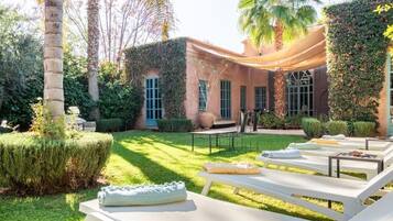 Une cour avec des fauteuils, une table et une pergola.