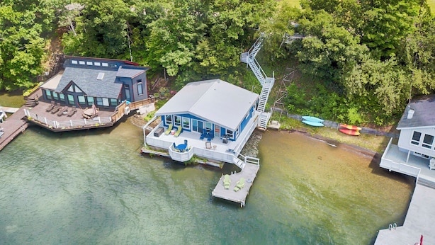 Une propriété située au bord de l’eau, dotée d’un quai, d’une maison avec une grande terrasse et d’un bâtiment séparé comprenant également un quai pour bateaux.