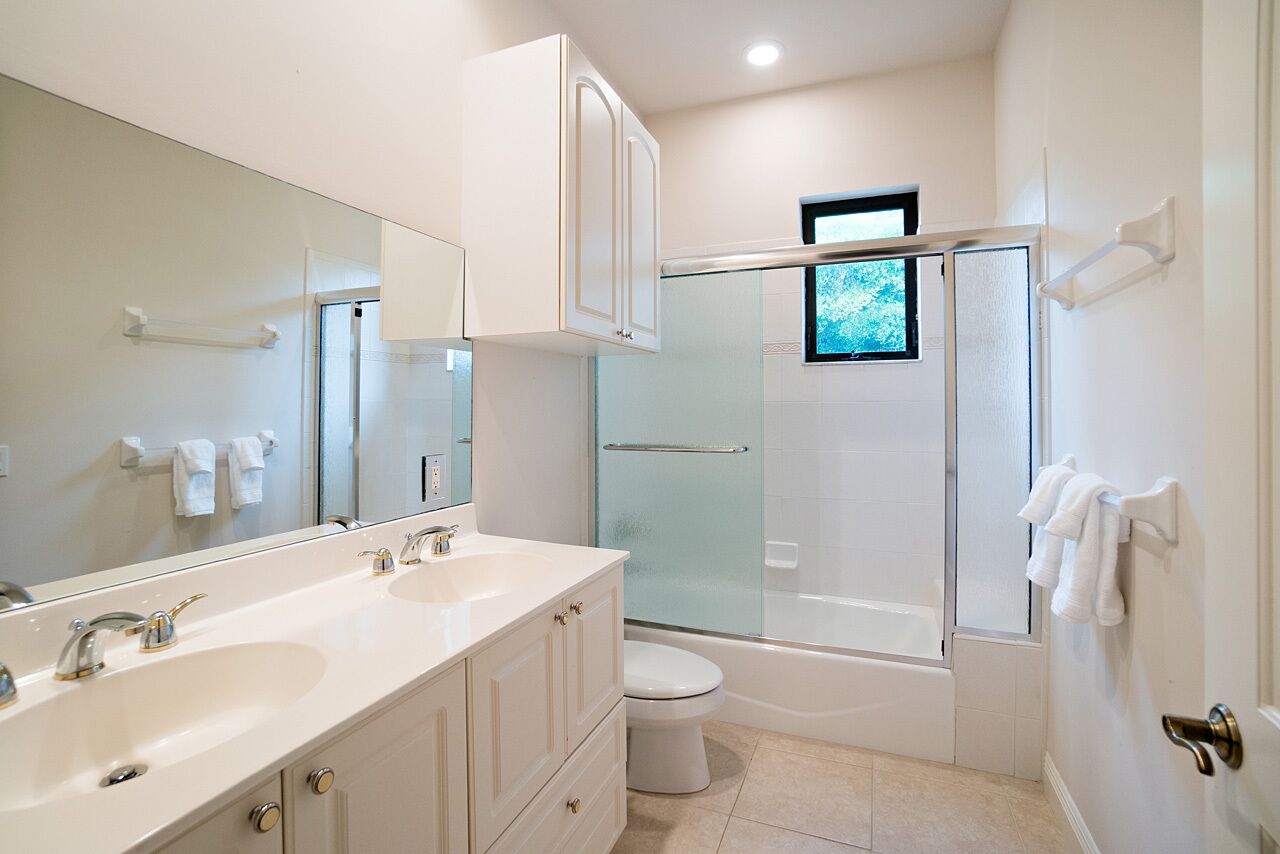 Une salle de bain moderne avec un meuble-lavabo à deux vasques, des toilettes, une baignoire et une douche à parois de verre.