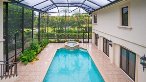 Une piscine couverte avec un jacuzzi, entourée d’un jardin et d’une maison.