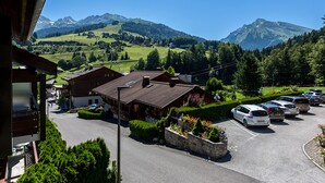 A mountain view with a parking lot, a building with a sloped roof, and a clear blue sky. - Village Center, Near Ski Slopes, Courses, and Shops (La Clusaz)