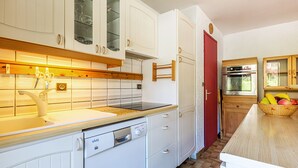 A kitchen with white cabinets, a red door, and a wooden countertop. - Village Center, Near Ski Slopes, Courses, and Shops (La Clusaz)