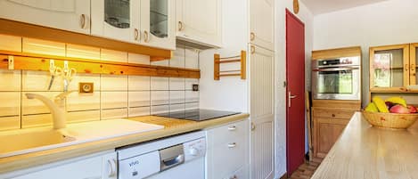 Ett kök med vita skåp, en röd dörr och en bänkskiva i trä.