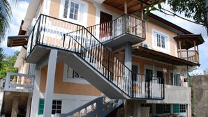 A multi-story building with a central staircase, balconies, and a mix of window styles. - Luxurious Rooms And Crisp, Virgin Mountain Air Awaits....Chef on Call (Cave Valley)