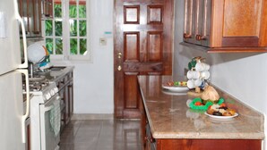 A kitchen with a stove, oven, and cabinets. There is a door with a window, and a countertop with plates and a bowl. - Luxurious Rooms And Crisp, Virgin Mountain Air Awaits....Chef on Call (Cave Valley)