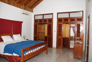 Ein Schlafzimmer mit einem hölzernen Bett, einem roten Vorhang und einem Schrank mit Glastüren.