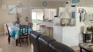 A dining area with a table set for four, a leather couch, and a kitchen area with a white brick backsplash. - Ground floor no stairs close to everything Atlantic side  (Marathon)