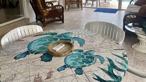 A dining area with a round table covered by a map-themed tablecloth, a television mounted on the wall, and a ceiling fan. - Ground floor no stairs close to everything Atlantic side  (Marathon)