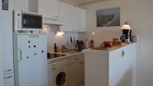 A compact kitchen with a microwave, oven, sink, and washing machine.