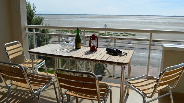 A balcony with a table and chairs, overlooking a river.