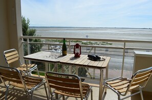 Ein Balkon mit Tisch und Stühlen mit Blick auf einen Fluss.